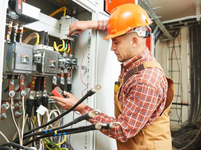 young adult electrician builder engineer worker in front of fuse switch board